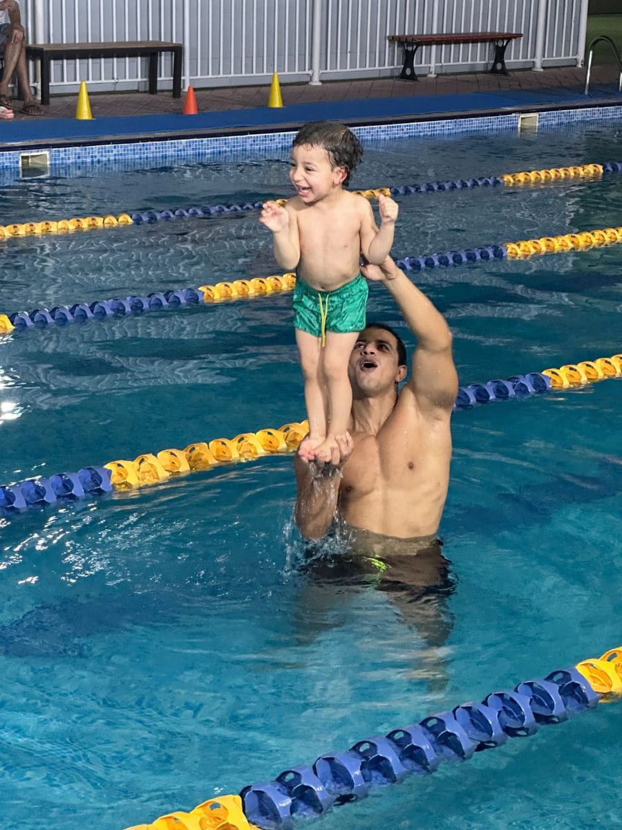 Captain Mahmoud lifting a toddler in the pool