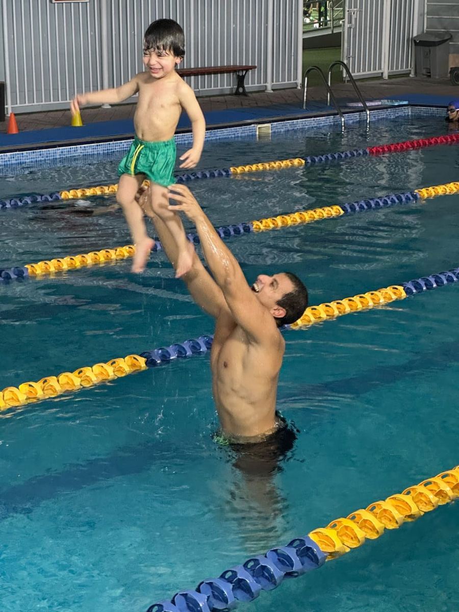 Captain Mahmoud lifting a happy toddler above the water during a lesson